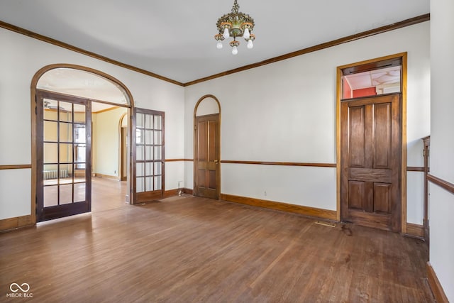 empty room featuring baseboards, ornamental molding, french doors, wood finished floors, and a notable chandelier