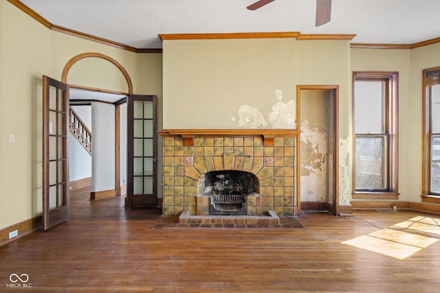 unfurnished living room with baseboards, wood finished floors, crown molding, and a tile fireplace