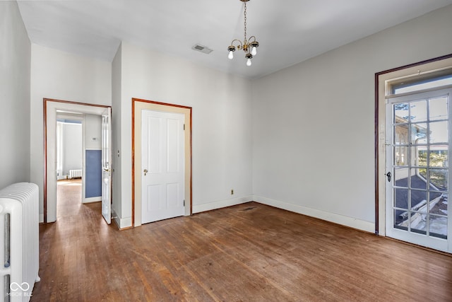 unfurnished bedroom with dark wood-type flooring, radiator, baseboards, and a chandelier