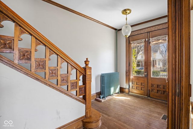 foyer entrance featuring wood finished floors, radiator heating unit, stairs, french doors, and crown molding