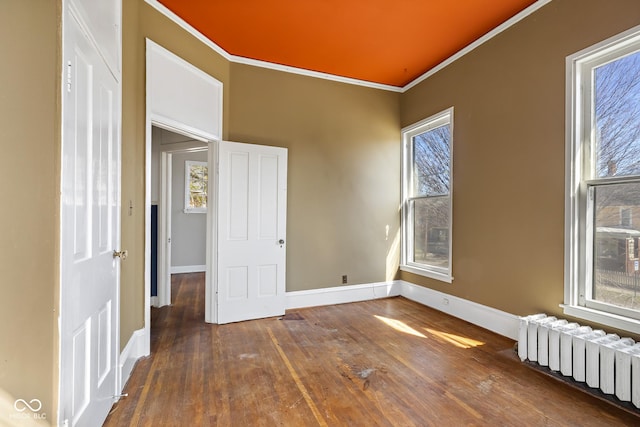 empty room with radiator, crown molding, baseboards, and wood-type flooring