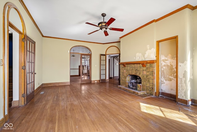 unfurnished living room featuring baseboards, arched walkways, and wood finished floors