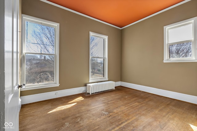 spare room with radiator, baseboards, wood-type flooring, and ornamental molding