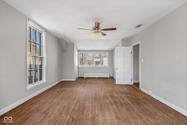 unfurnished living room with visible vents, radiator, wood finished floors, and baseboards