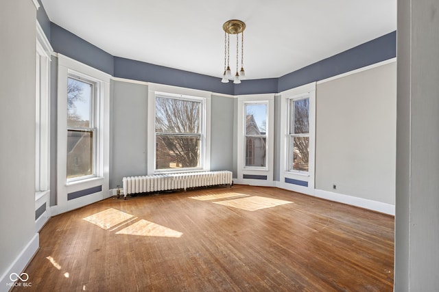 unfurnished dining area with baseboards, hardwood / wood-style floors, and radiator heating unit