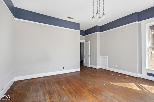 spare room featuring visible vents, wood-type flooring, and baseboards