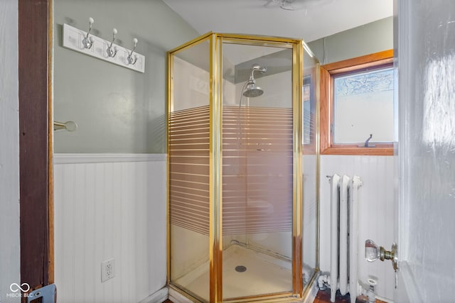 bathroom featuring radiator, wainscoting, and a shower stall