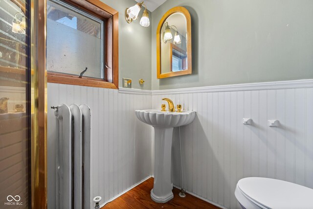 bathroom featuring a wainscoted wall, radiator, toilet, and wood finished floors