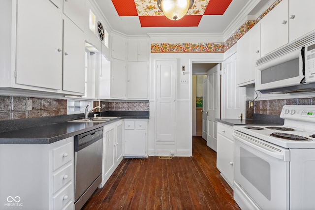 kitchen featuring dark countertops, white cabinets, white appliances, and a sink