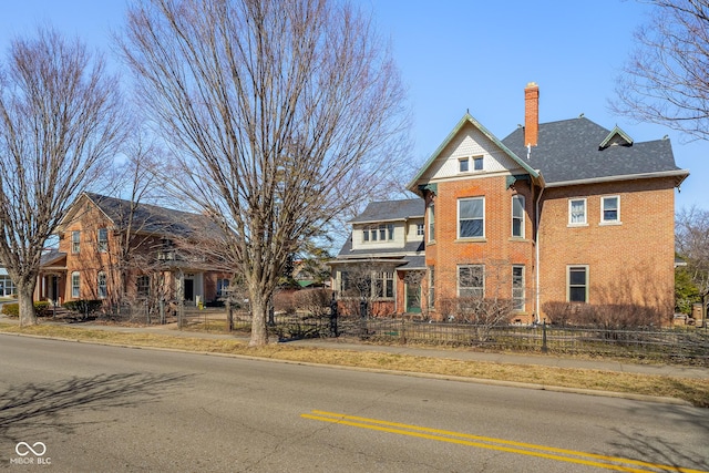 view of front of home featuring brick siding, a fenced front yard, and a chimney