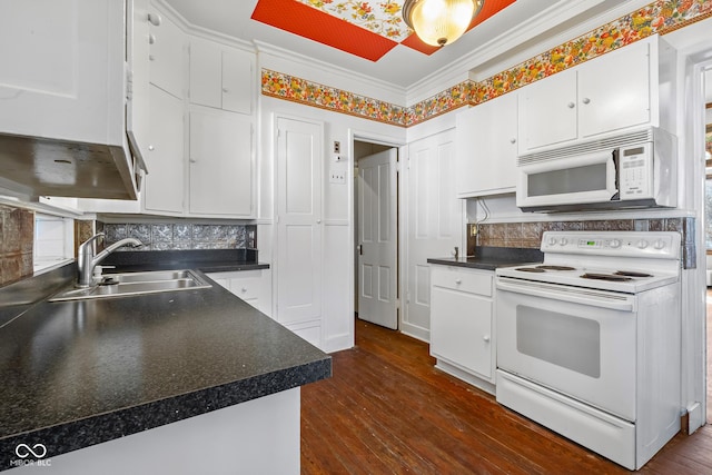 kitchen with ornamental molding, a sink, dark countertops, white cabinetry, and white appliances