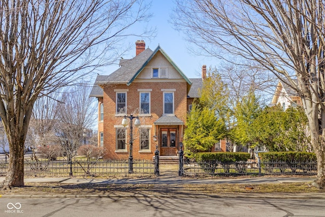 view of front of house with a fenced front yard, brick siding, and a chimney