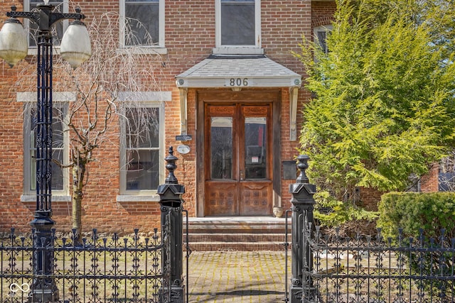 property entrance featuring fence and brick siding