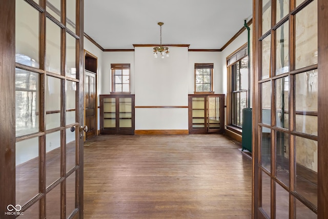 unfurnished room with ornamental molding, wood finished floors, french doors, baseboards, and a chandelier