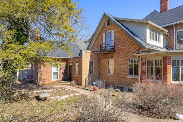 rear view of house with brick siding and a balcony