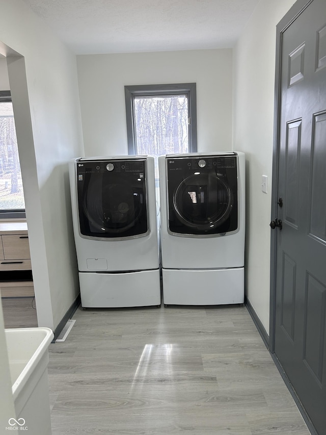 laundry room featuring laundry area, light wood-style flooring, baseboards, and separate washer and dryer