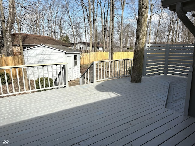 deck featuring a storage unit, an outbuilding, and fence