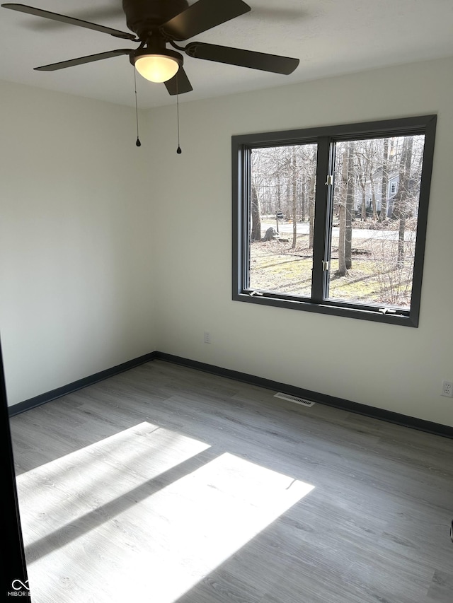 unfurnished room featuring wood finished floors, visible vents, baseboards, and ceiling fan