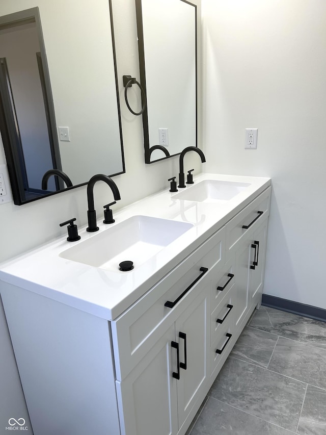 bathroom with double vanity, baseboards, and a sink