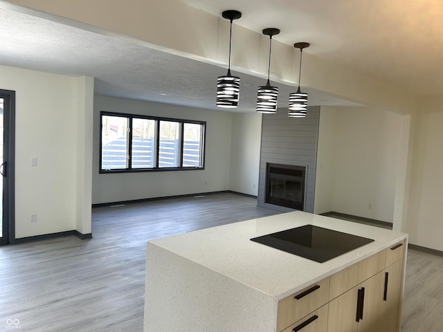 kitchen featuring modern cabinets, light wood-style flooring, light brown cabinets, light stone counters, and a textured ceiling