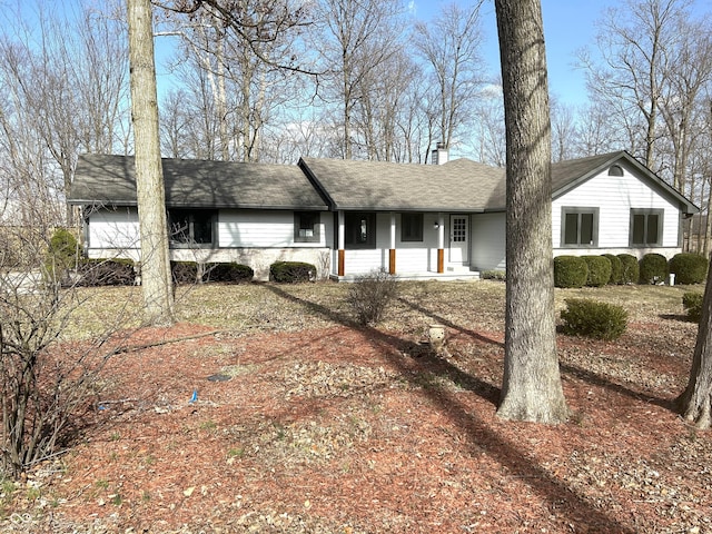 ranch-style home with a shingled roof and a chimney