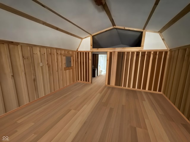 additional living space with electric panel, lofted ceiling, and wood finished floors