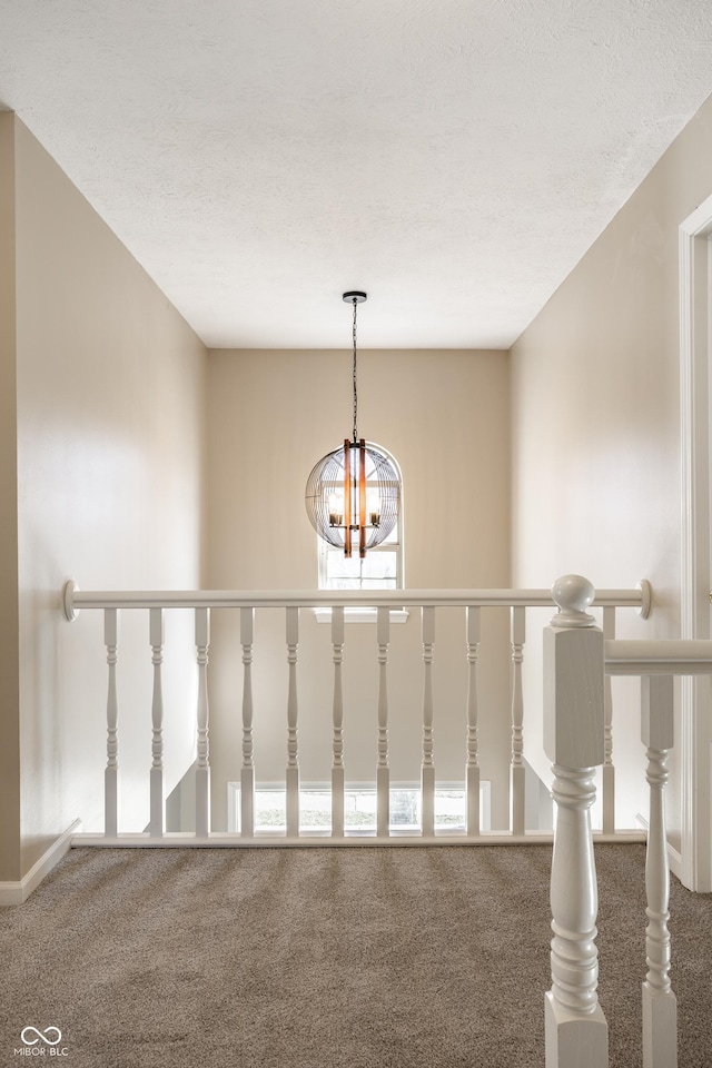 hallway featuring a notable chandelier and carpet flooring