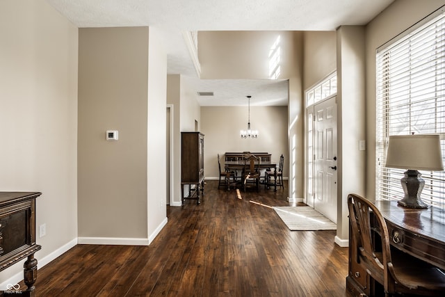 foyer entrance featuring baseboards, a notable chandelier, and dark wood-style floors