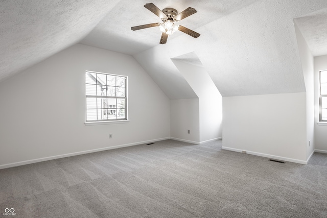 bonus room featuring baseboards, carpet floors, a textured ceiling, and vaulted ceiling