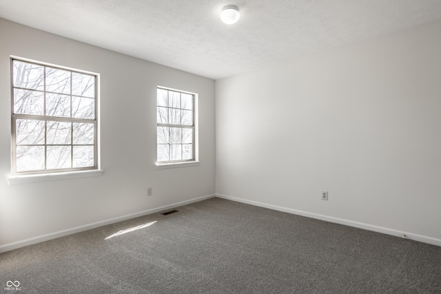 carpeted empty room featuring baseboards, visible vents, and a textured ceiling