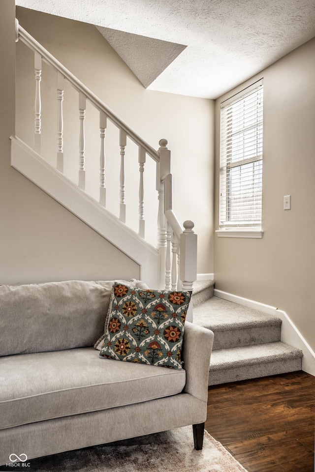 stairs featuring a textured ceiling, baseboards, and wood finished floors