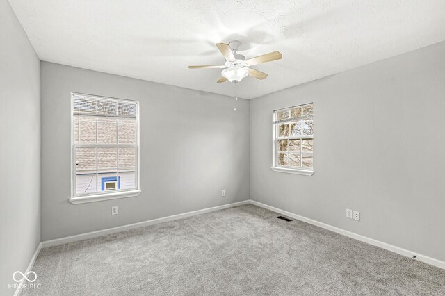 carpeted spare room featuring a ceiling fan and baseboards