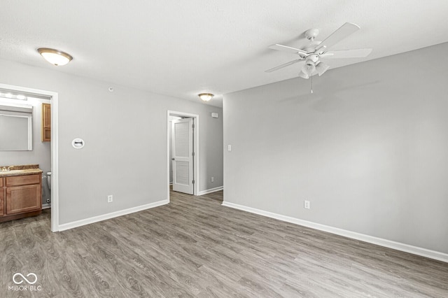 unfurnished bedroom with ensuite bathroom, light wood-type flooring, and baseboards