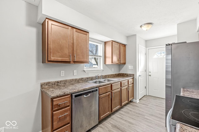 kitchen with brown cabinetry, light wood-style flooring, a sink, electric stove, and dishwasher