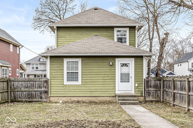 view of front facade with a fenced backyard, entry steps, and roof with shingles