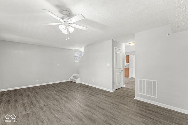 below grade area with dark wood finished floors, visible vents, a textured ceiling, and stairs