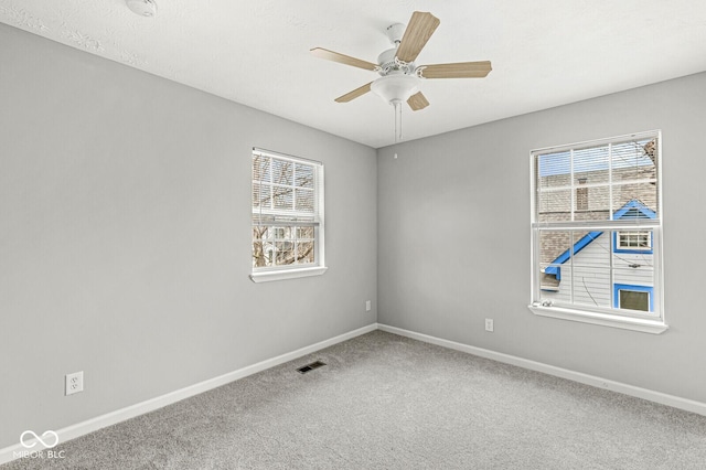 carpeted empty room featuring visible vents, baseboards, and a ceiling fan