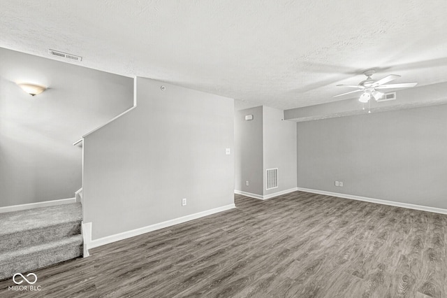 unfurnished living room with visible vents, a ceiling fan, a textured ceiling, wood finished floors, and stairs