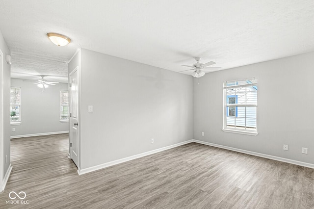 empty room with plenty of natural light, baseboards, and wood finished floors