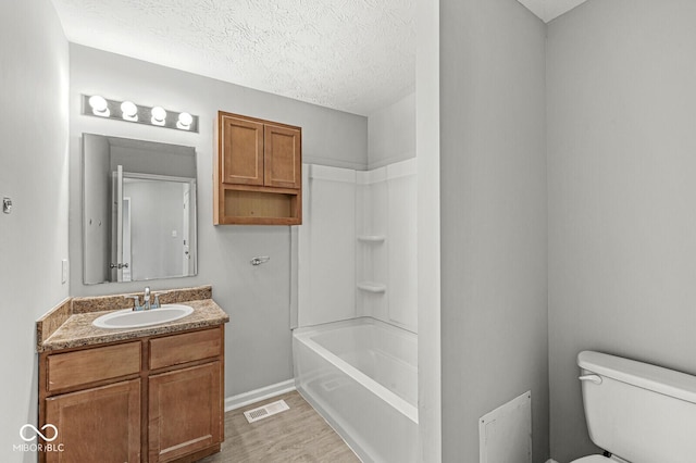 bathroom with vanity, wood finished floors, visible vents, a textured ceiling, and toilet