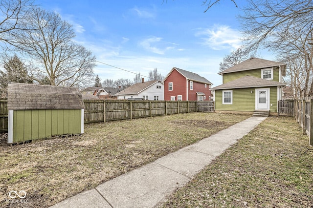 view of yard featuring entry steps, an outdoor structure, and a fenced backyard