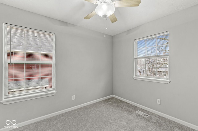 empty room with a ceiling fan, baseboards, visible vents, and carpet floors