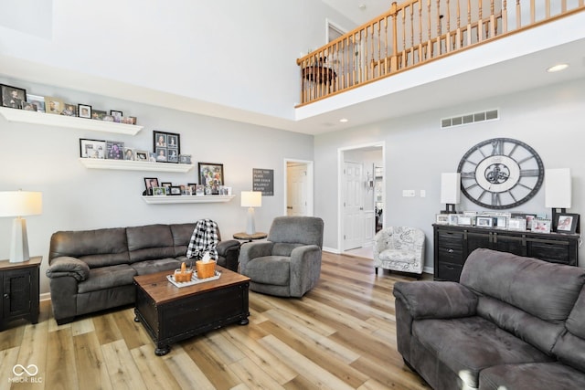 living area featuring visible vents, wood finished floors, recessed lighting, baseboards, and a towering ceiling