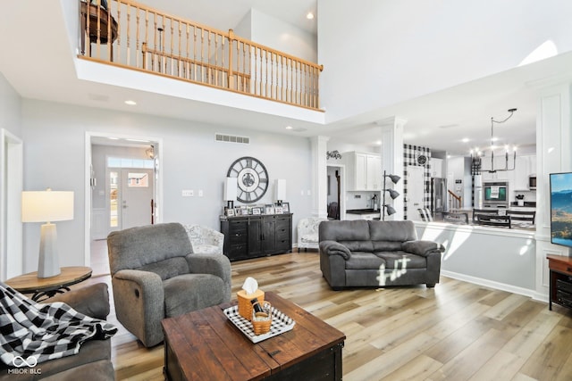 living room with visible vents, ornate columns, a high ceiling, recessed lighting, and light wood-type flooring