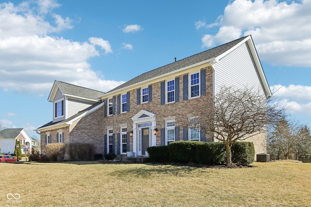 colonial house featuring brick siding and a front lawn