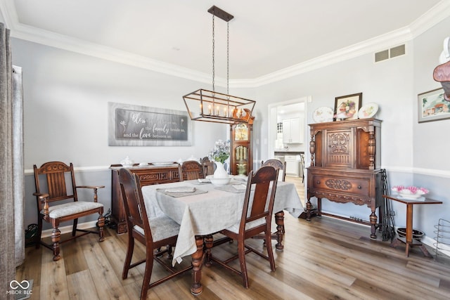 dining room featuring visible vents, crown molding, and wood finished floors