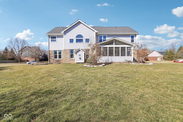 rear view of property featuring a yard and a sunroom