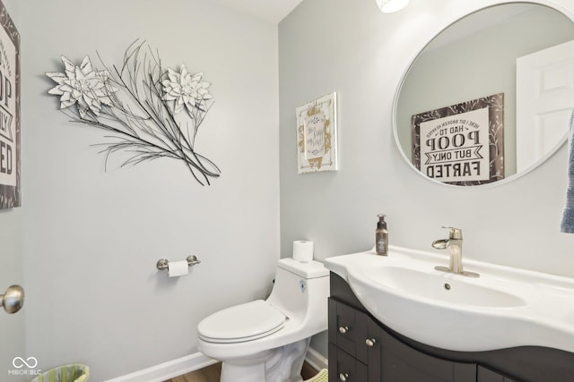 bathroom featuring toilet, vanity, and baseboards