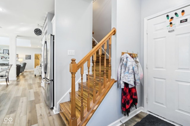 entryway with stairway, baseboards, and light wood finished floors