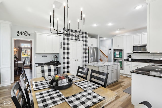 kitchen with a sink, tasteful backsplash, stainless steel appliances, light wood-style floors, and white cabinets